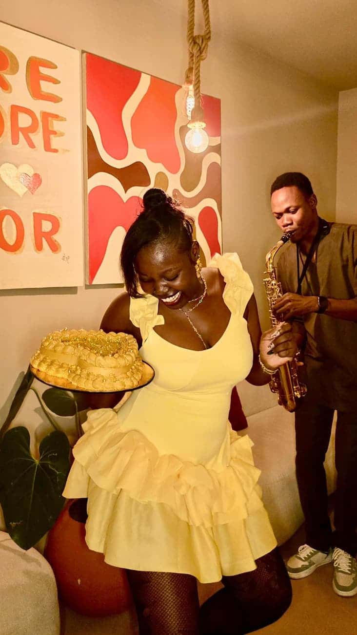 Woman holds cake as saxophonist plays