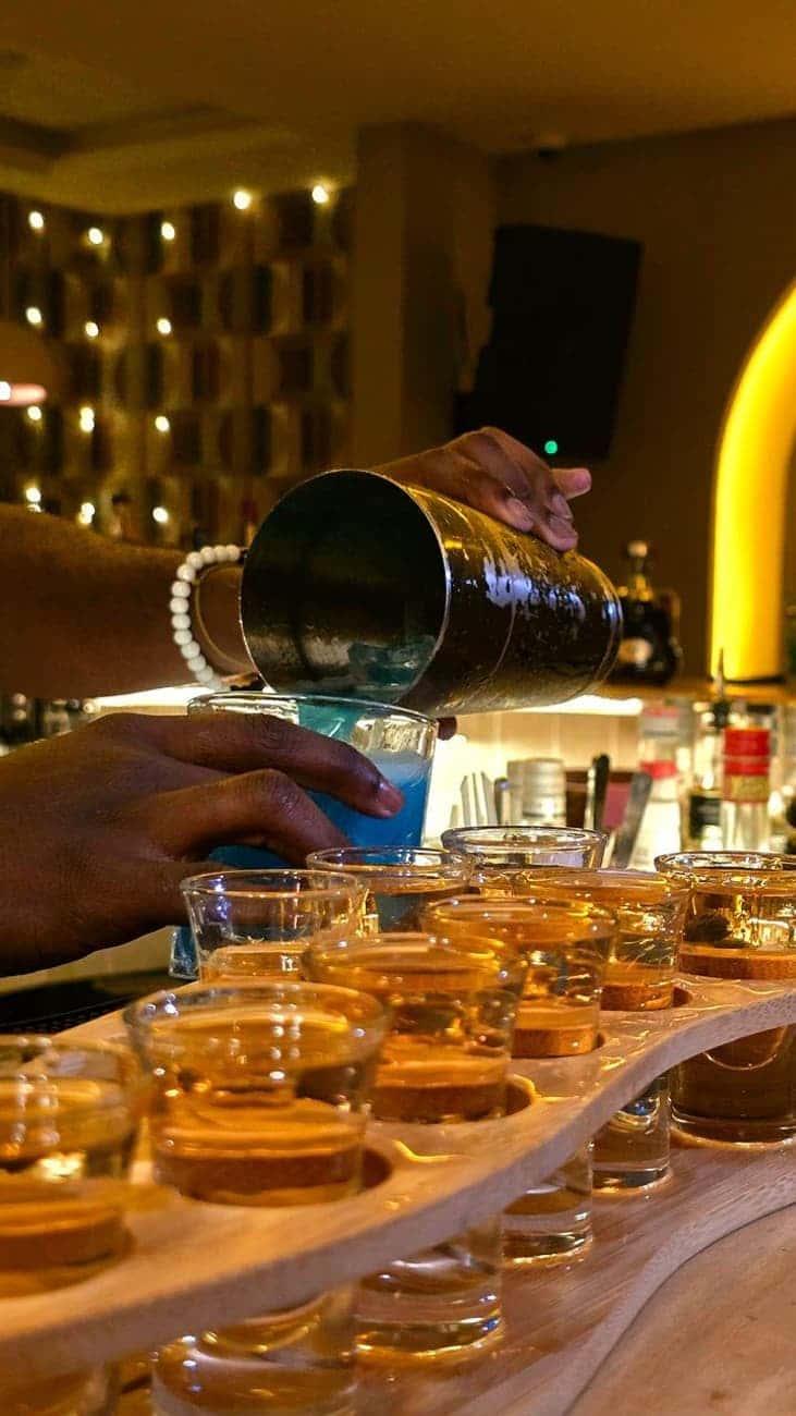 Bartender pouring blue cocktail, shots lined up