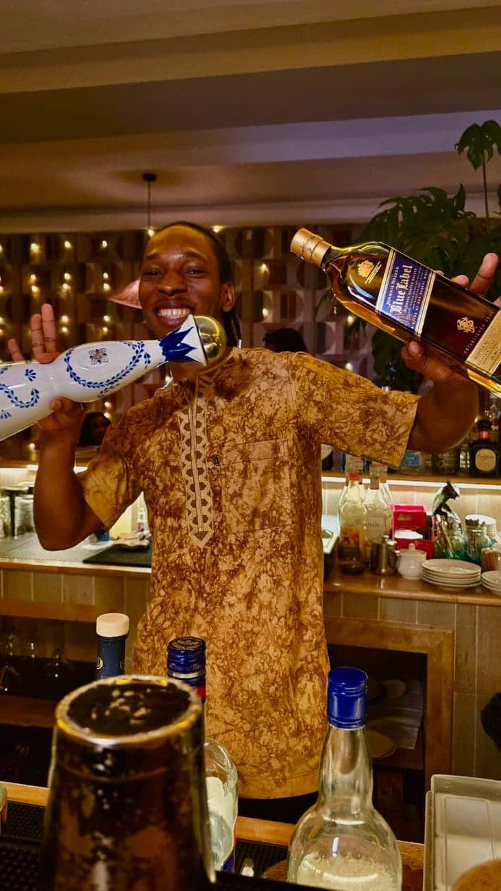 Smiling bartender holding up bottles